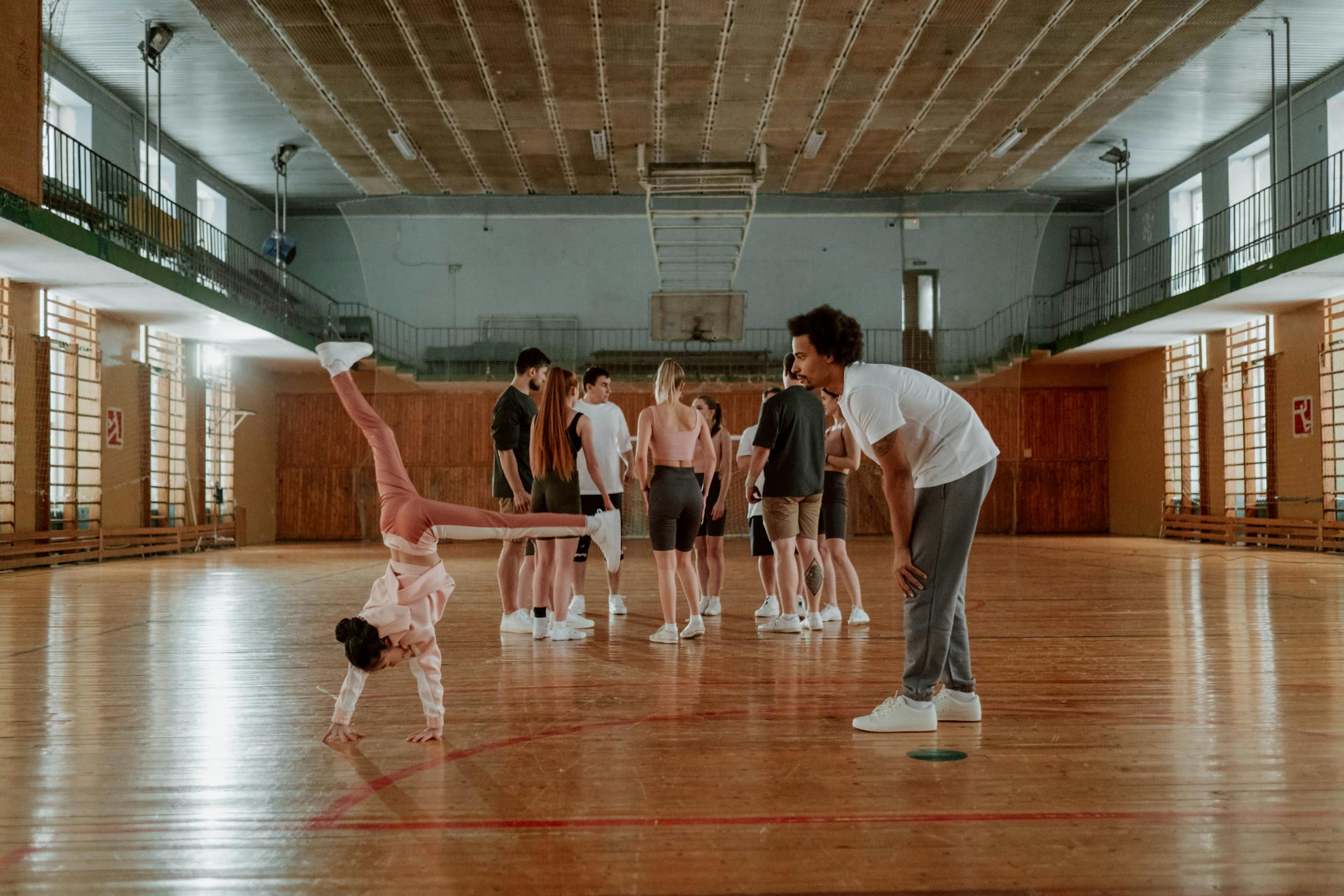 Young girl practicing gymnastics in a lively indoor gym environment with a coach.